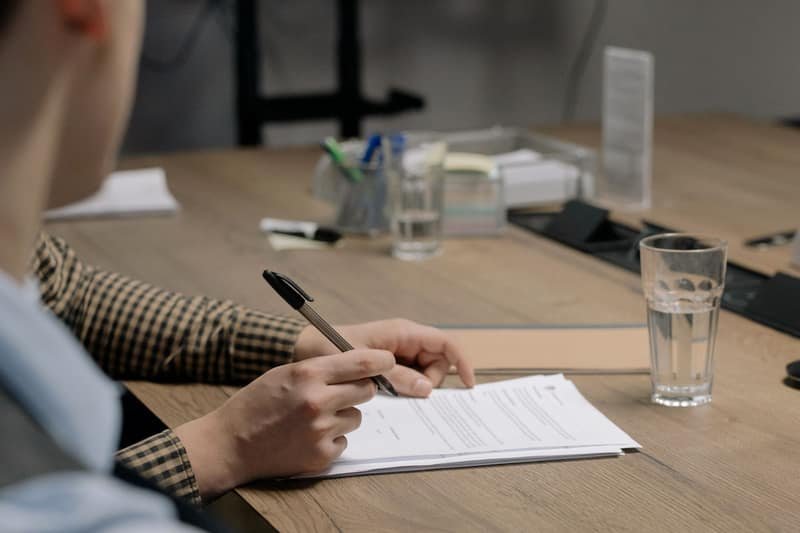 A person completing and signing official application paperwork at a desk